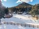 Charming cabin exterior featuring a wooden deck, set against a snowy landscape with a mountain in the background at 8537 S Doubleheader Hwy, Morrison, CO 80465