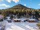 Quaint log cabins covered in snow with convenient parking, set against a backdrop of lush trees and mountain at 8537 S Doubleheader Hwy, Morrison, CO 80465