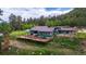 Inviting home with a large wooden deck, surrounded by lush greenery and mature trees at 8537 S Doubleheader Hwy, Morrison, CO 80465