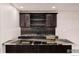 Basement wet bar with dark cabinetry and granite countertop at 1369 Burt Ave, Berthoud, CO 80513