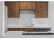 Close up on a modern kitchen with white subway tile backsplash, stainless steel sink, and wood cabinets at 7665 E Eastman Ave # D304, Denver, CO 80231