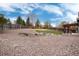Large backyard featuring gravel, a wooden fence, grass, mature trees, and patio area at 13093 Hudson St, Thornton, CO 80241