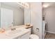 Bright bathroom featuring a vanity with sink and mirror, toilet, and a washer and dryer in the corner at 13093 Hudson St, Thornton, CO 80241