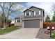 A two-story home with a gray exterior, brick accents, a well-kept lawn, and a spacious driveway at 13093 Hudson St, Thornton, CO 80241