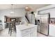 Open kitchen area with island and stainless refrigerator adjacent to the dining area and staircase at 13093 Hudson St, Thornton, CO 80241