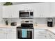 Close-up of kitchen appliances, with stainless steel microwave, stove, and a white tile backsplash at 13093 Hudson St, Thornton, CO 80241