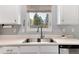Kitchen sink under a window with white cabinetry and stainless steel appliances at 13093 Hudson St, Thornton, CO 80241
