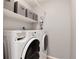 Laundry area equipped with a modern washing machine and dryer, and storage shelves above at 13093 Hudson St, Thornton, CO 80241