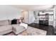 Open-concept living space with hardwood floors, a comfortable sofa, and view of kitchen with bar seating at 13093 Hudson St, Thornton, CO 80241