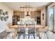 Elegant dining area featuring a wooden table, stylish chairs, modern lighting, and a view of the kitchen at 13806 Honey Hush Trl, Parker, CO 80134