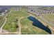 Expansive aerial shot of the community, featuring a golf course, pond, and residential area, showcasing the community's amenities at 15565 E 115Th Ave, Commerce City, CO 80022
