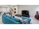 Comfortable finished basement area with a plush blue sofa, television, and adjacent staircase at 15565 E 115Th Ave, Commerce City, CO 80022
