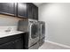 Well-equipped laundry room with modern washer and dryer, utility sink, and dark cabinets for storage at 15565 E 115Th Ave, Commerce City, CO 80022