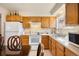 Functional kitchen with wood cabinets, white appliances, and a view from the table at 1173 Dallas St, Aurora, CO 80010
