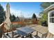 Wooden deck with a table, chairs, umbrella, and a grill overlooking trees and mountains at 5929 Dunraven Way, Golden, CO 80403