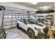 A well-organized garage with a white SUV, storage shelves, and overhead storage at 5929 Dunraven Way, Golden, CO 80403