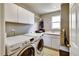 Convenient laundry room equipped with washer, dryer, storage cabinets, and a utility sink for added functionality at 5929 Dunraven Way, Golden, CO 80403