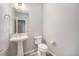 Elegant powder room featuring a pedestal sink, toilet, and sleek fixtures, offering convenience and style at 8948 Delacorte St, Littleton, CO 80129