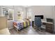 Bright bedroom with a colorful patterned bed, desk, grey wood floors, and large windows providing ample natural light at 8948 Delacorte St, Highlands Ranch, CO 80129