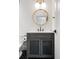 Stylish powder room with a round mirror, modern vanity, and herringbone flooring at 1308 Stuart St, Denver, CO 80204