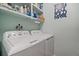 Functional laundry room with washer, dryer, storage shelves, and fresh paint at 10624 W Berry Pl, Littleton, CO 80127