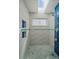 Modern shower with blue and white textured tiles, a built-in niche, and a shower window at 10624 W Berry Pl, Littleton, CO 80127