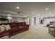 Finished basement featuring a plush red sectional sofa, neutral carpet, and recessed lighting at 5485 S Lakeview St, Littleton, CO 80120