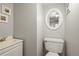 Cozy half bathroom with a white toilet, white vanity, and a decorative round mirror at 5485 S Lakeview St, Littleton, CO 80120