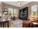 Cozy home office featuring a black bookcase, a comfortable leather chair, and ample natural light from multiple windows at 13794 E Caley Dr, Englewood, CO 80111