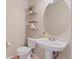 Powder room featuring a pedestal sink, round mirror, and decorative shelving at 7720 Brown Bear Way, Littleton, CO 80125