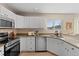 Kitchen with stainless steel appliances, granite countertops, tile backsplash and white cabinetry at 7720 Brown Bear Way, Littleton, CO 80125