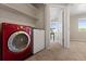 Modern laundry room featuring a red washer and white dryer next to an open door to the bedroom at 7720 Brown Bear Way, Littleton, CO 80125