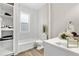 Clean bathroom featuring a tub with marble-style tile surround, open shelving, and modern fixtures at 3045 Arapahoe St, Denver, CO 80205