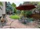 Backyard dining area with stone patio surrounded by mature trees and lush landscaping at 8316 Green Island Cir, Lone Tree, CO 80124