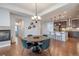 Open-concept dining room with a round wooden table and stylish teal chairs, flowing into a modern kitchen at 15392 W 49Th Ave, Golden, CO 80403