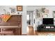 View of living room with upright piano, television with console, hardwood floors and trim, and colorful art at 3202 S Dahlia St, Denver, CO 80222