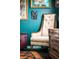 Close up detail of eclectic sitting area with vintage chair, wood furnishings, area rug, and colorful artistic decor at 3202 S Dahlia St, Denver, CO 80222