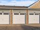 Three-car garage with white doors numbered 163, 164, and 165 with brick and siding accents at 12802 Jasmine St # B, Thornton, CO 80602