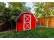 Charming red barn-style shed with white trim, adding character to the backyard at 16291 E 7Th Dr, Aurora, CO 80011