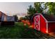 A backyard featuring a charming red barn-style shed, lush green lawn, and a covered hot tub at 16291 E 7Th Dr, Aurora, CO 80011