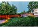 Backyard view showcasing lush green lawn with a wood fence and an upper deck with covered hot tub feature at 16291 E 7Th Dr, Aurora, CO 80011