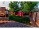 A backyard featuring a charming red barn-style shed, lush green lawn, and pathway lighting for evening ambiance at 16291 E 7Th Dr, Aurora, CO 80011