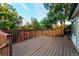 Large wooden deck overlooking the backyard, featuring a charming red barn-style shed and mature trees at 16291 E 7Th Dr, Aurora, CO 80011