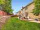 Expansive backyard with a retaining wall, lush grass, and a stone patio perfect for outdoor entertaining at 2544 S Fundy Cir, Aurora, CO 80013