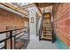 Staircase to upper level with metal railings, wooden steps, and brick walls at 1515 N Ogden St # 7, Denver, CO 80218