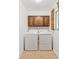 Well-lit laundry room featuring a side-by-side washer and dryer with upper cabinets at 8484 E Radcliff Ave, Denver, CO 80237