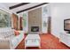 Cozy living room boasts a brick fireplace, carpeted floor, beamed ceiling, and large windows at 8484 E Radcliff Ave, Denver, CO 80237