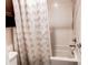 This tiled tub and shower features a white decorative shower curtain and a shower head on an adjustable bar at 10152 Southlawn Cir, Commerce City, CO 80022