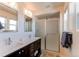 Modern bathroom featuring a double sink vanity, glass-enclosed shower, and ample natural light from a large window at 10152 Southlawn Cir, Commerce City, CO 80022