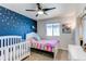 The bedroom features a double bed next to a crib and blue star-themed accent wall at 10152 Southlawn Cir, Commerce City, CO 80022